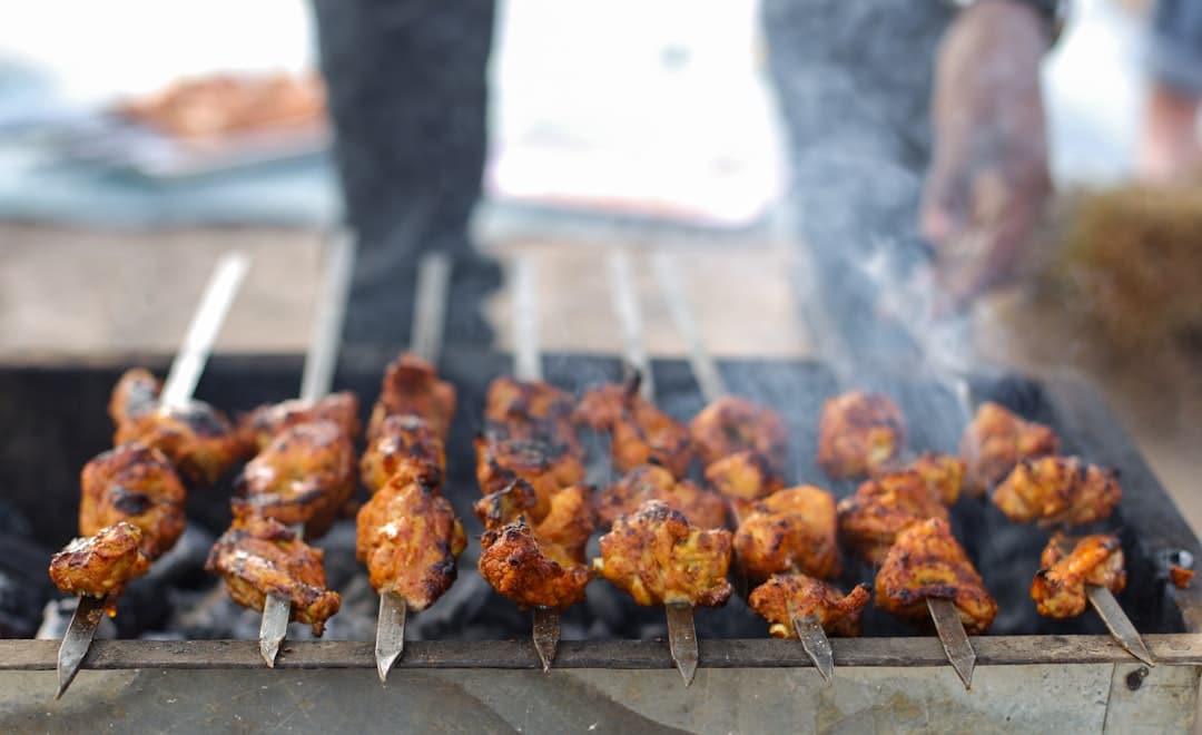 indian style chicken skewers sizzling on grill with tandoori char and smoke